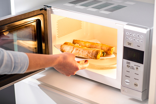 close up of a woman baking pastry in microwave oven.